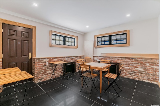 tiled dining room featuring brick wall