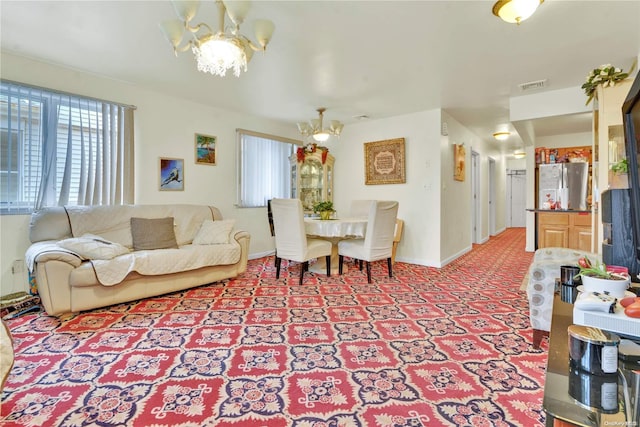 living room featuring plenty of natural light, light colored carpet, and an inviting chandelier