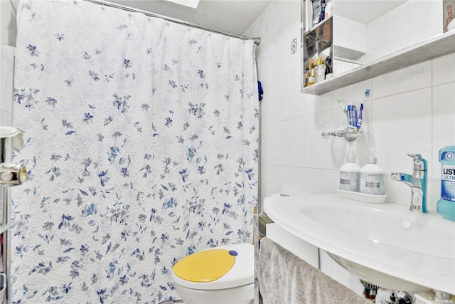 bathroom featuring sink, curtained shower, toilet, and tile walls