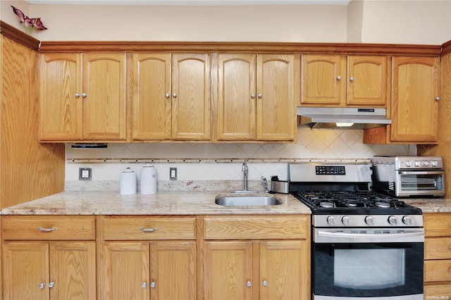 kitchen with light stone countertops, sink, tasteful backsplash, and stainless steel gas range