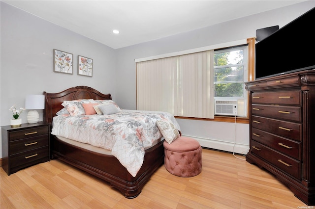 bedroom featuring light hardwood / wood-style floors, a baseboard radiator, and cooling unit