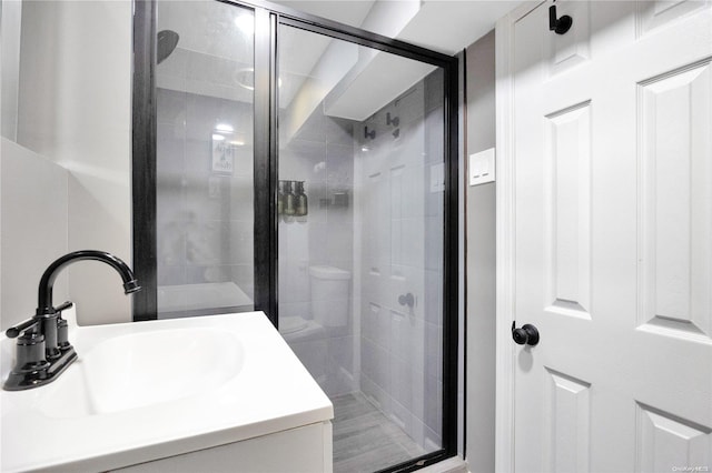 bathroom with toilet, a shower with shower door, and sink