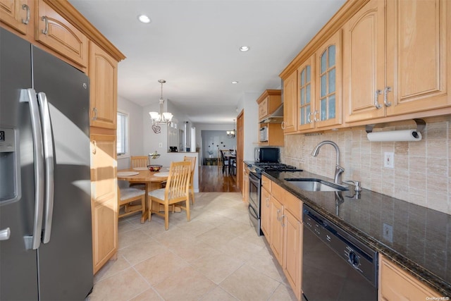 kitchen with appliances with stainless steel finishes, dark stone counters, sink, decorative light fixtures, and a chandelier