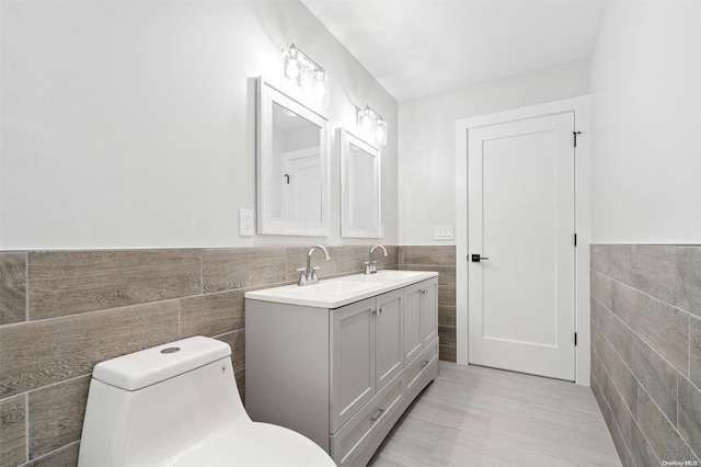 bathroom featuring vanity, tile walls, and toilet