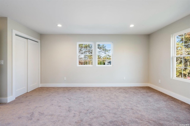 unfurnished bedroom with light carpet and a closet