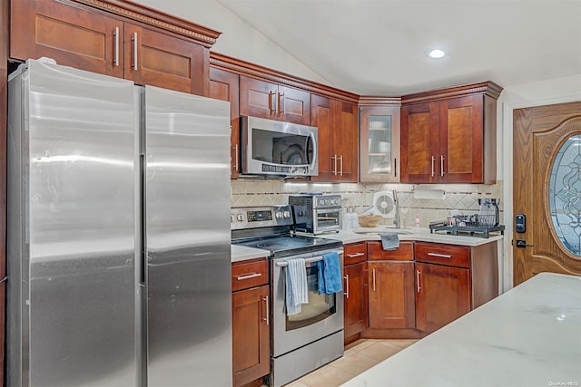 kitchen with backsplash, light tile patterned floors, lofted ceiling, and appliances with stainless steel finishes