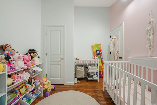 bedroom with a crib and dark wood-type flooring