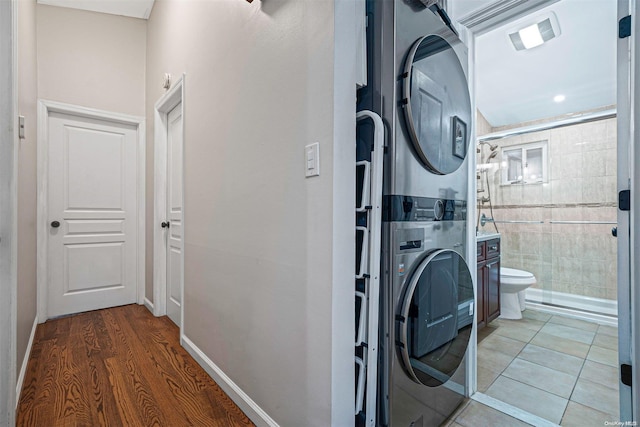 laundry area with hardwood / wood-style floors and stacked washer / drying machine