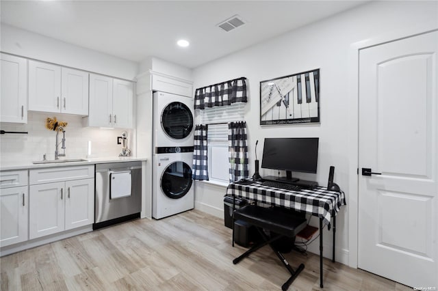 clothes washing area featuring sink, stacked washer and clothes dryer, and light wood-type flooring