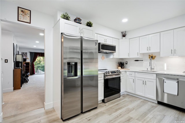 kitchen with white cabinetry, sink, light hardwood / wood-style floors, and appliances with stainless steel finishes