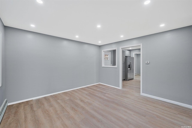 empty room featuring light wood-type flooring and baseboard heating