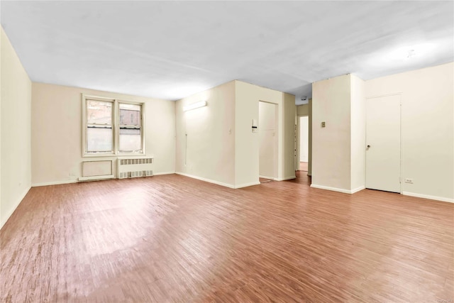 spare room featuring radiator and light hardwood / wood-style floors