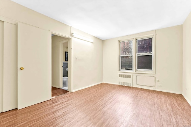 unfurnished room featuring radiator heating unit and hardwood / wood-style flooring