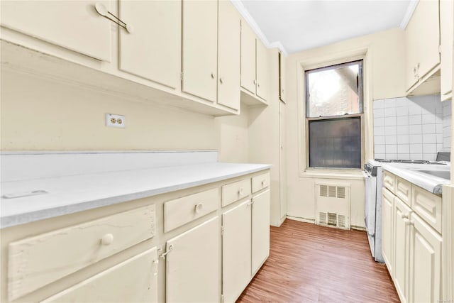 kitchen with range with gas stovetop, tasteful backsplash, light hardwood / wood-style floors, and ornamental molding