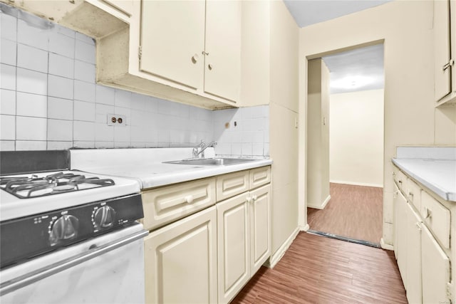 kitchen featuring sink, hardwood / wood-style floors, range with gas stovetop, and cream cabinetry