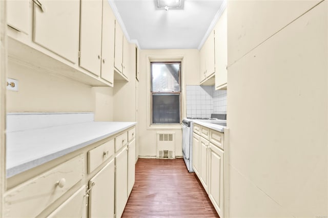 kitchen with hardwood / wood-style flooring, cream cabinetry, backsplash, and gas stove