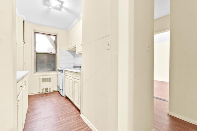 kitchen with white cabinets, light hardwood / wood-style floors, backsplash, and white range with gas cooktop