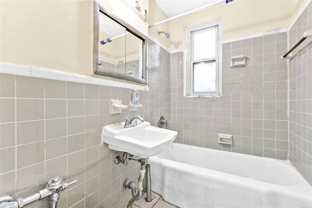 bathroom with tile walls, tiled shower / bath, and sink