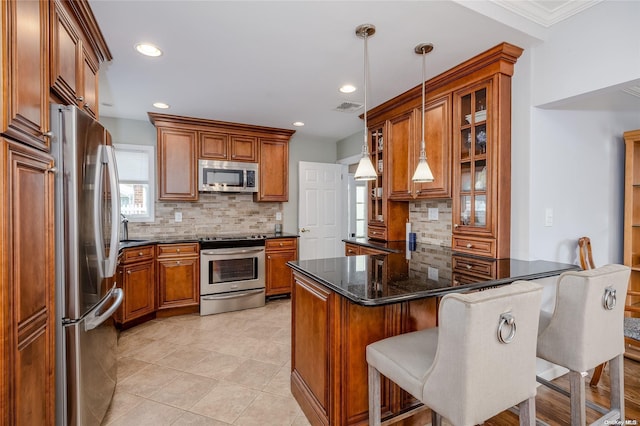 kitchen featuring hanging light fixtures, a kitchen breakfast bar, backsplash, crown molding, and appliances with stainless steel finishes