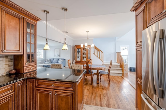 kitchen with hanging light fixtures, stainless steel refrigerator, plenty of natural light, and light hardwood / wood-style floors