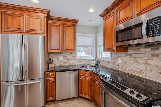 kitchen featuring sink, tasteful backsplash, dark stone countertops, light tile patterned floors, and appliances with stainless steel finishes