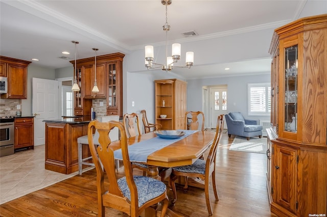 dining area featuring ornamental molding, light hardwood / wood-style flooring, and an inviting chandelier