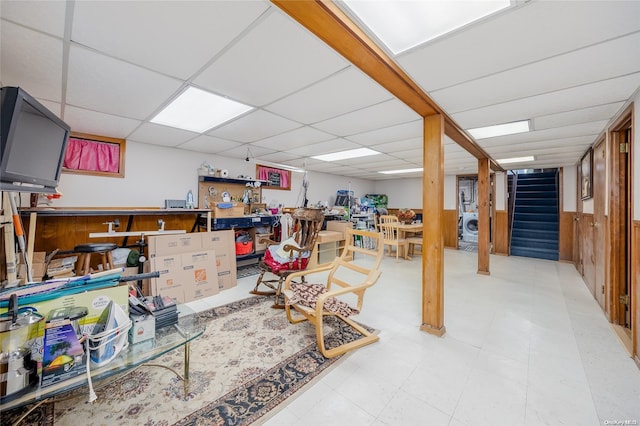 basement with a drop ceiling and wooden walls