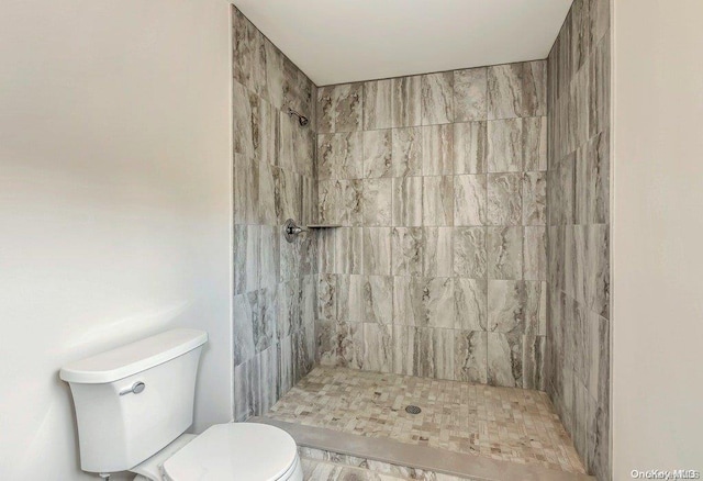 bathroom with a tile shower and toilet