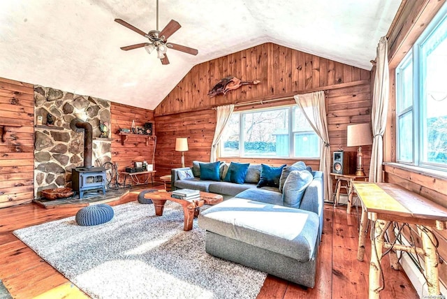 living room featuring hardwood / wood-style flooring, wood walls, and a wood stove