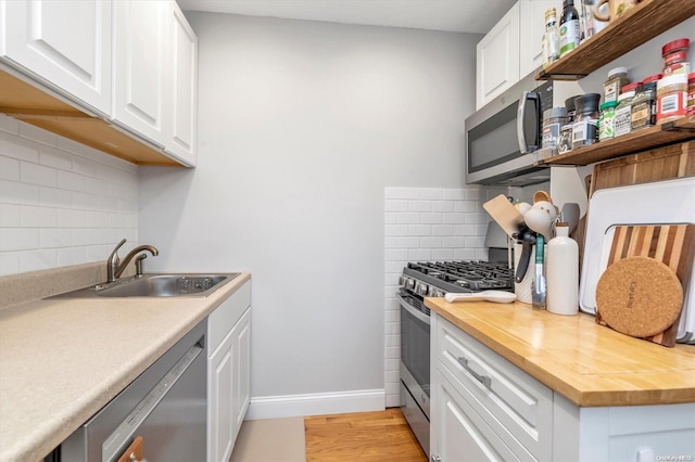 kitchen featuring appliances with stainless steel finishes, light hardwood / wood-style floors, white cabinetry, and tasteful backsplash