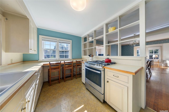 kitchen with a wealth of natural light, stainless steel gas stove, light hardwood / wood-style floors, and ornamental molding