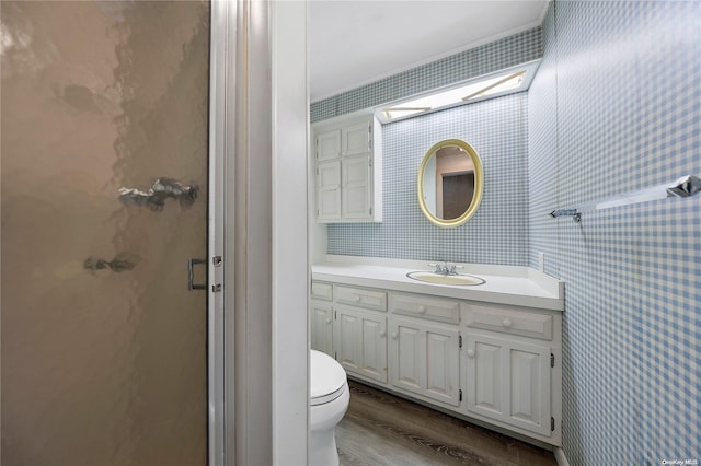 bathroom with wood-type flooring, vanity, toilet, and walk in shower