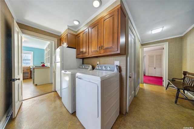 laundry area featuring cabinets, crown molding, and washing machine and clothes dryer