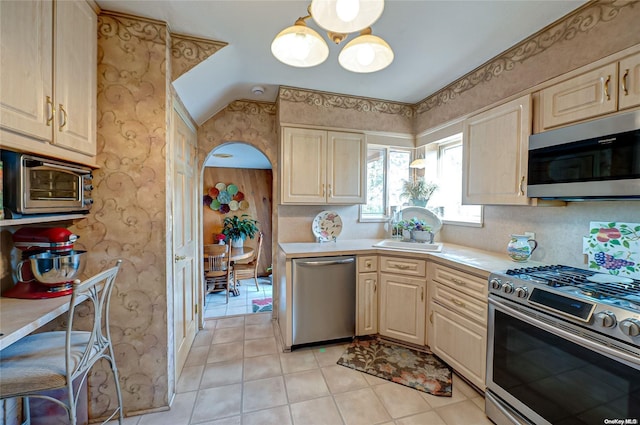 kitchen featuring light tile patterned floors, stainless steel appliances, lofted ceiling, and sink