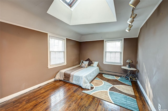 bedroom featuring baseboard heating, multiple windows, and hardwood / wood-style flooring