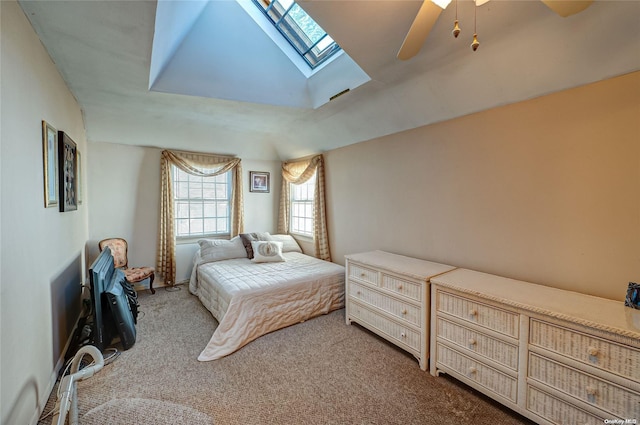 bedroom with ceiling fan, vaulted ceiling with skylight, and carpet floors