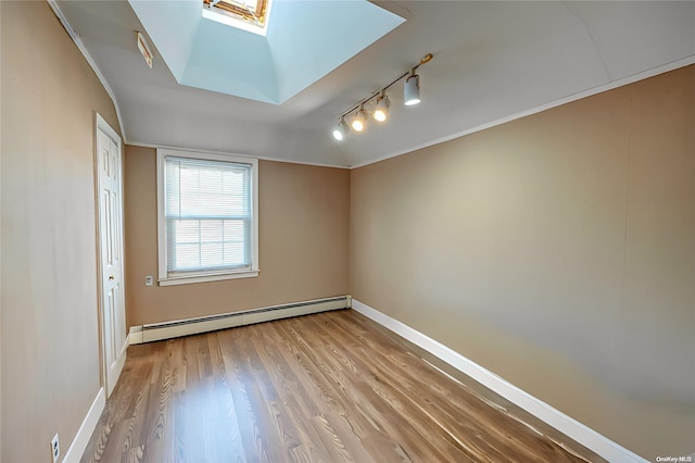 empty room featuring a skylight, crown molding, light hardwood / wood-style floors, and a baseboard heating unit