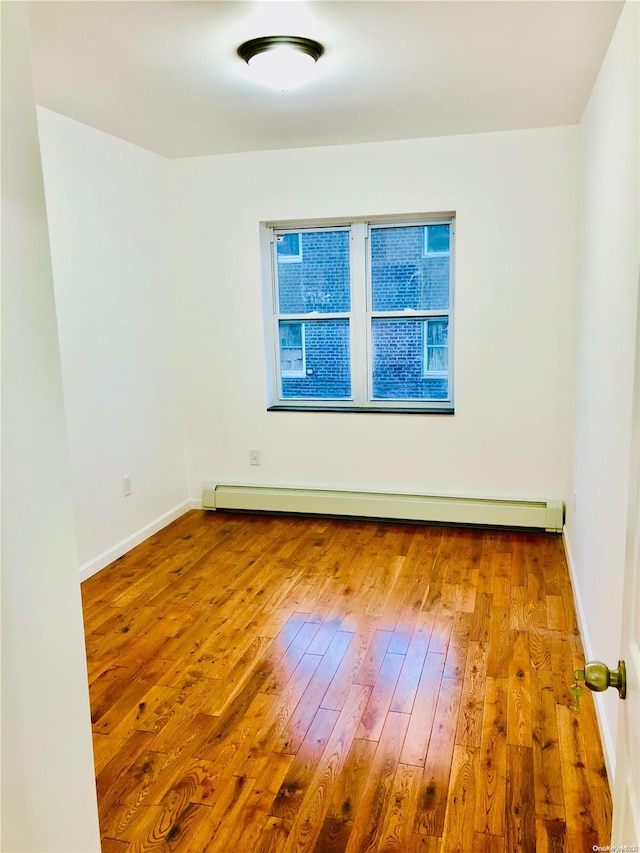 unfurnished room with hardwood / wood-style floors and baseboard heating