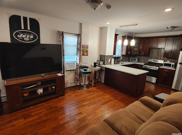 kitchen featuring kitchen peninsula, dark hardwood / wood-style floors, decorative light fixtures, dark brown cabinets, and stainless steel appliances