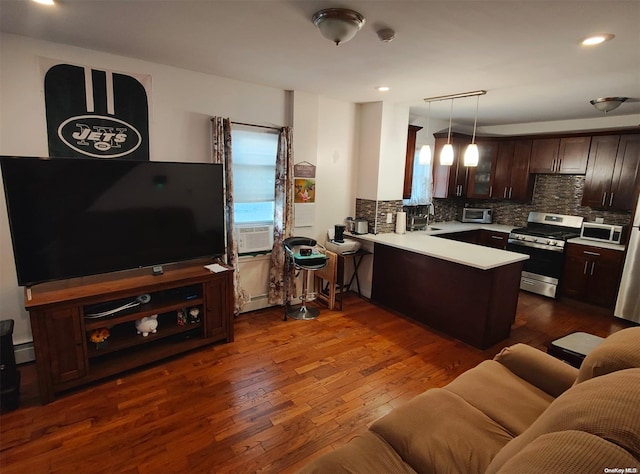 kitchen featuring dark hardwood / wood-style floors, stainless steel range oven, kitchen peninsula, decorative light fixtures, and decorative backsplash