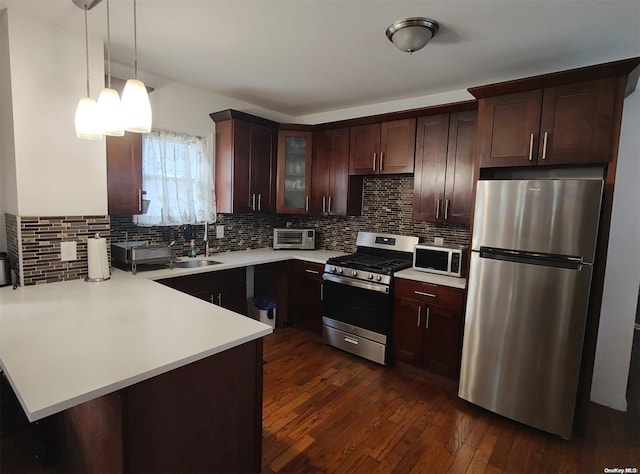 kitchen with decorative light fixtures, dark hardwood / wood-style floors, kitchen peninsula, and stainless steel appliances