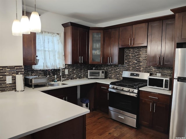 kitchen with sink, dark wood-type flooring, stainless steel appliances, backsplash, and decorative light fixtures