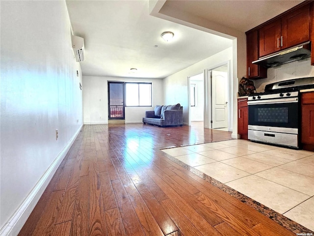 kitchen with light hardwood / wood-style flooring, stainless steel electric stove, an AC wall unit, and range hood