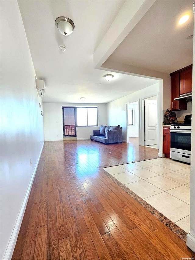 unfurnished living room featuring a wall mounted air conditioner and light hardwood / wood-style floors