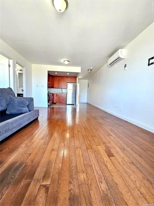 unfurnished living room featuring hardwood / wood-style floors and a wall mounted AC