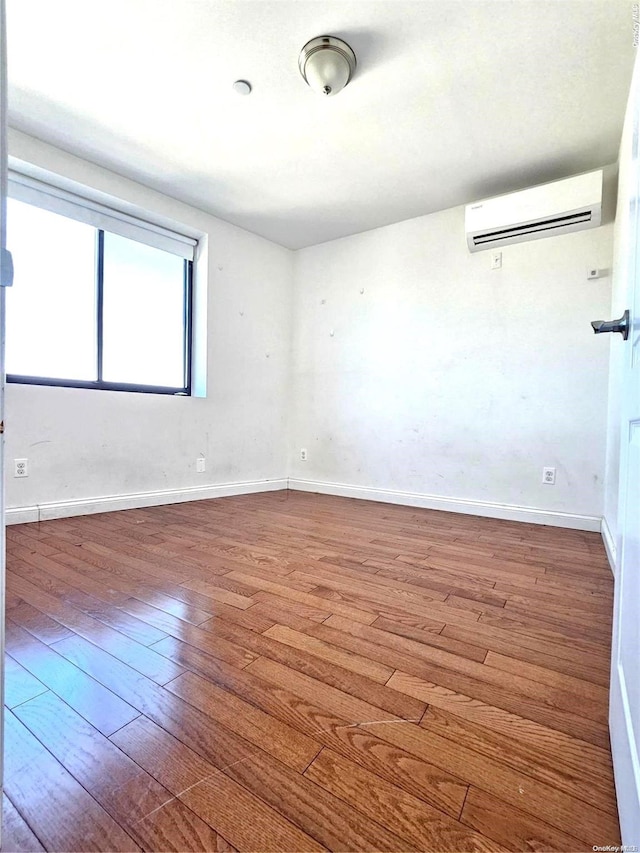 unfurnished room with a wall mounted air conditioner and wood-type flooring