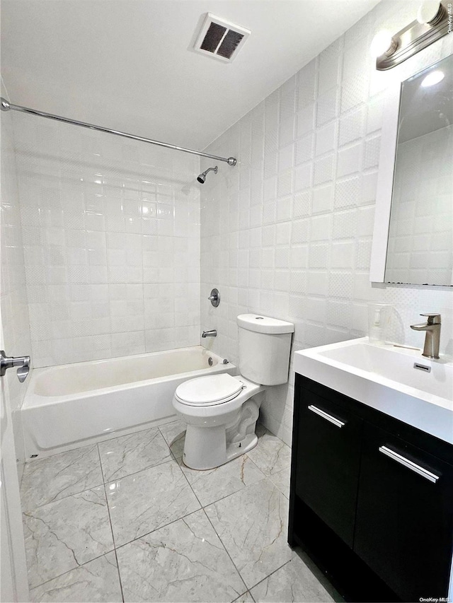 full bathroom with tiled shower / bath, vanity, toilet, and tile walls