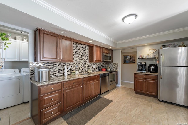 kitchen with light stone countertops, sink, appliances with stainless steel finishes, washer and dryer, and ornamental molding