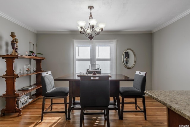 dining space with ornamental molding, wood finished floors, and a chandelier
