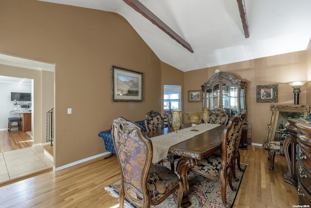 dining room with baseboards, light wood-type flooring, and high vaulted ceiling